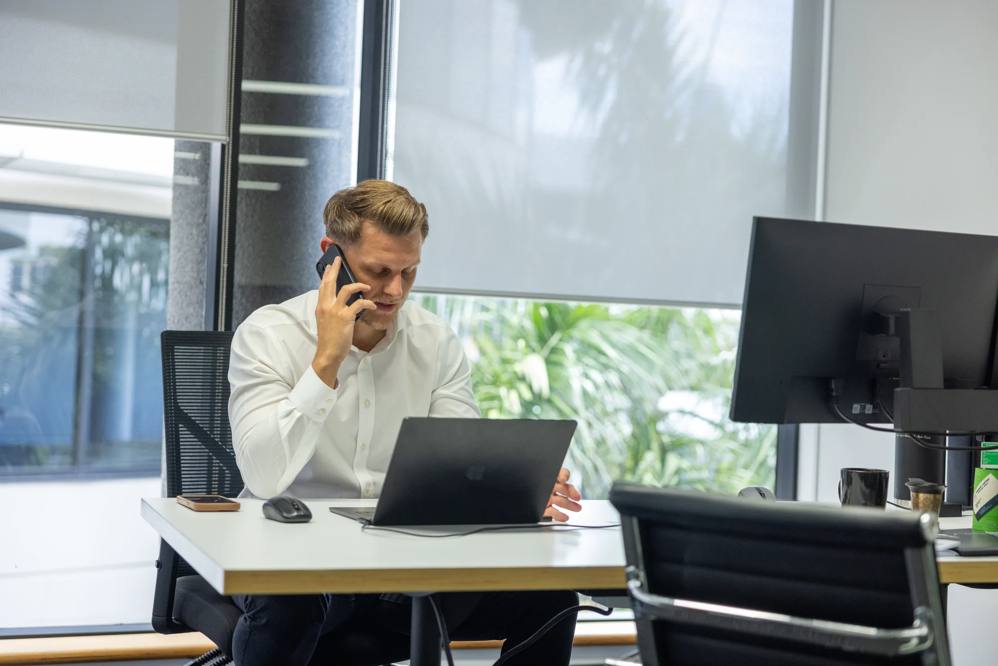 2 office ladies seated at a desk in discussion